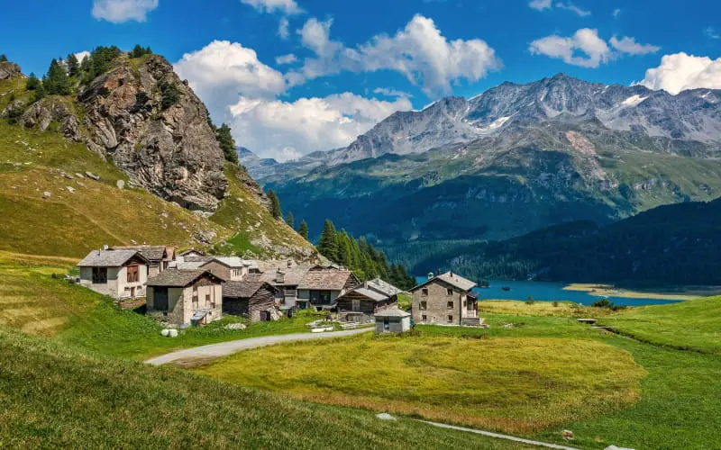 A Swiss village with traditional stone houses against a backdrop of mountains 