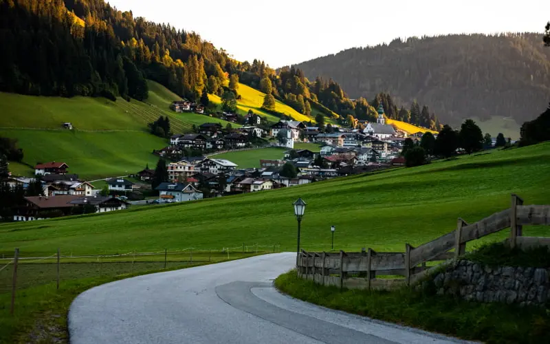 a scenic view of a village in Switzerland, with a winding road leading towards it