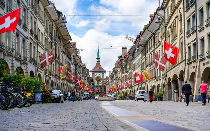A street in Bern with flags and a clock tower